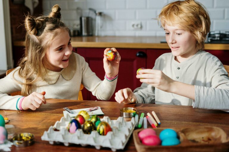 Two children enjoy decorating colorful Easter eggs indoors with creativity and fun.